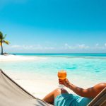 Słoneczna plaża z turkusową wodą i palmami.