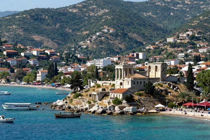 Widok na wybrzeże Kusadasi z ruinami i łodziami.